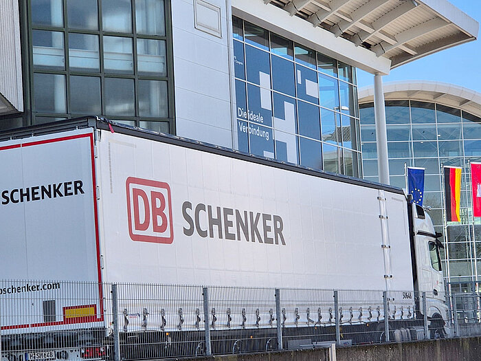 Truck with the inscription "DB Schenker" in front of the exhibition halls